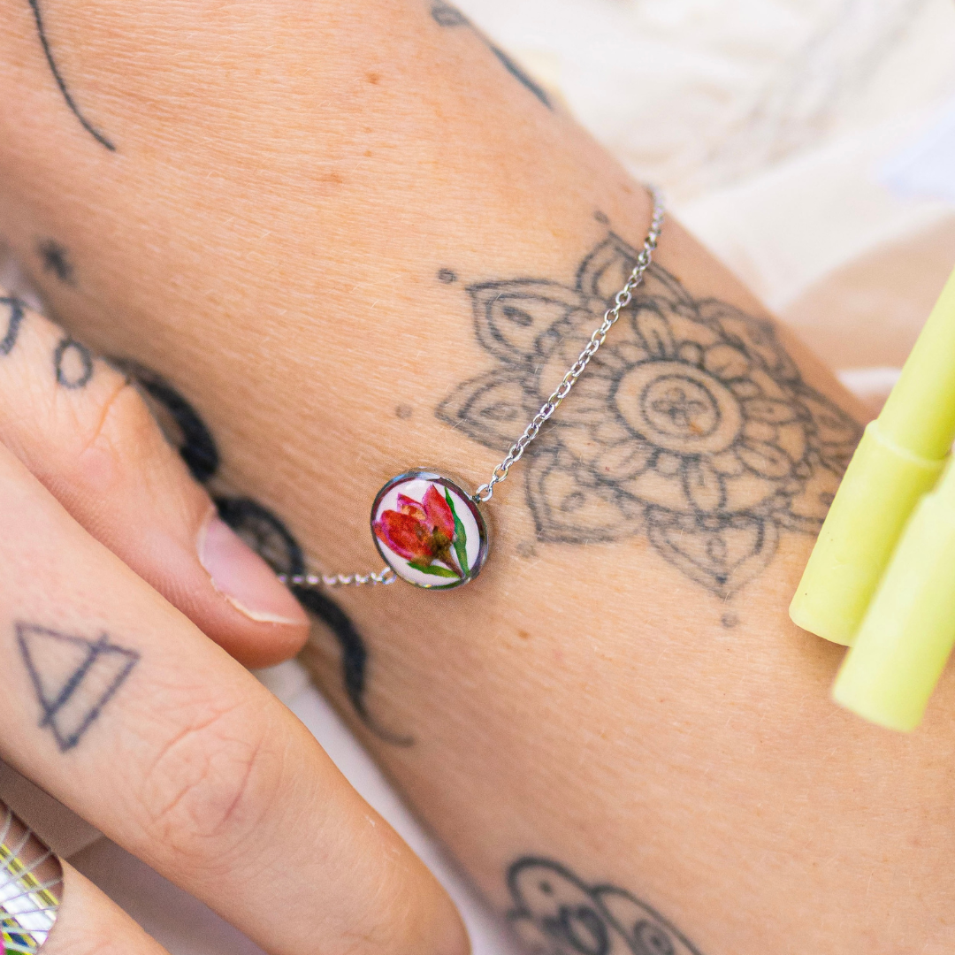 Bracciale in acciaio inossidabile con ciondolo in resina e fiore selvatico rosa con sfondo bianco