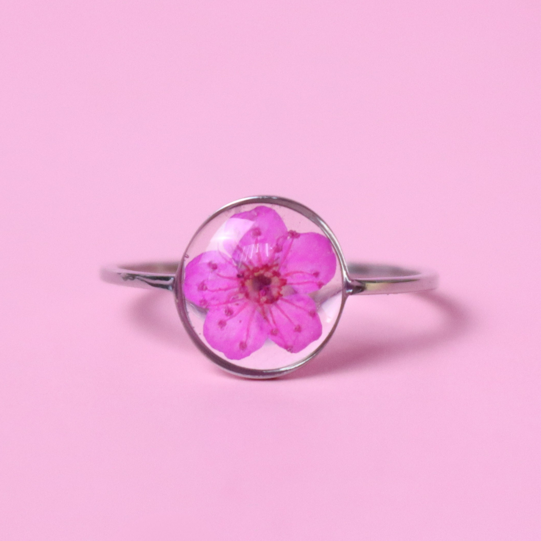 Anello in acciaio inox e fiore selvatico fucsia intersecato nella resina