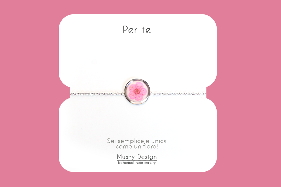 Bracciale in acciaio inossidabile con ciondolo in resina e fiore selvatico rosa con sfondo bianco