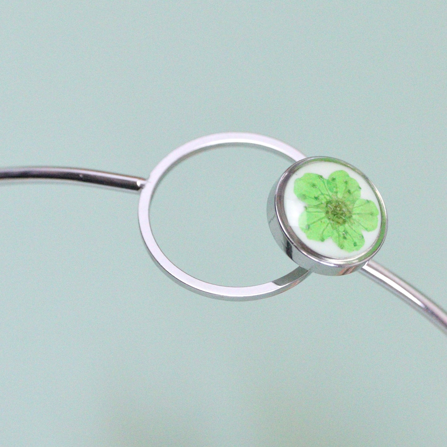 Bracciale ABBRACCIAMI in acciaio inox con resina e fiore selvatico verde