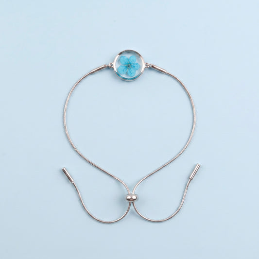 Bracciale scorrevole in acciaio inox e fiore azzurro preservato nel ciondolo