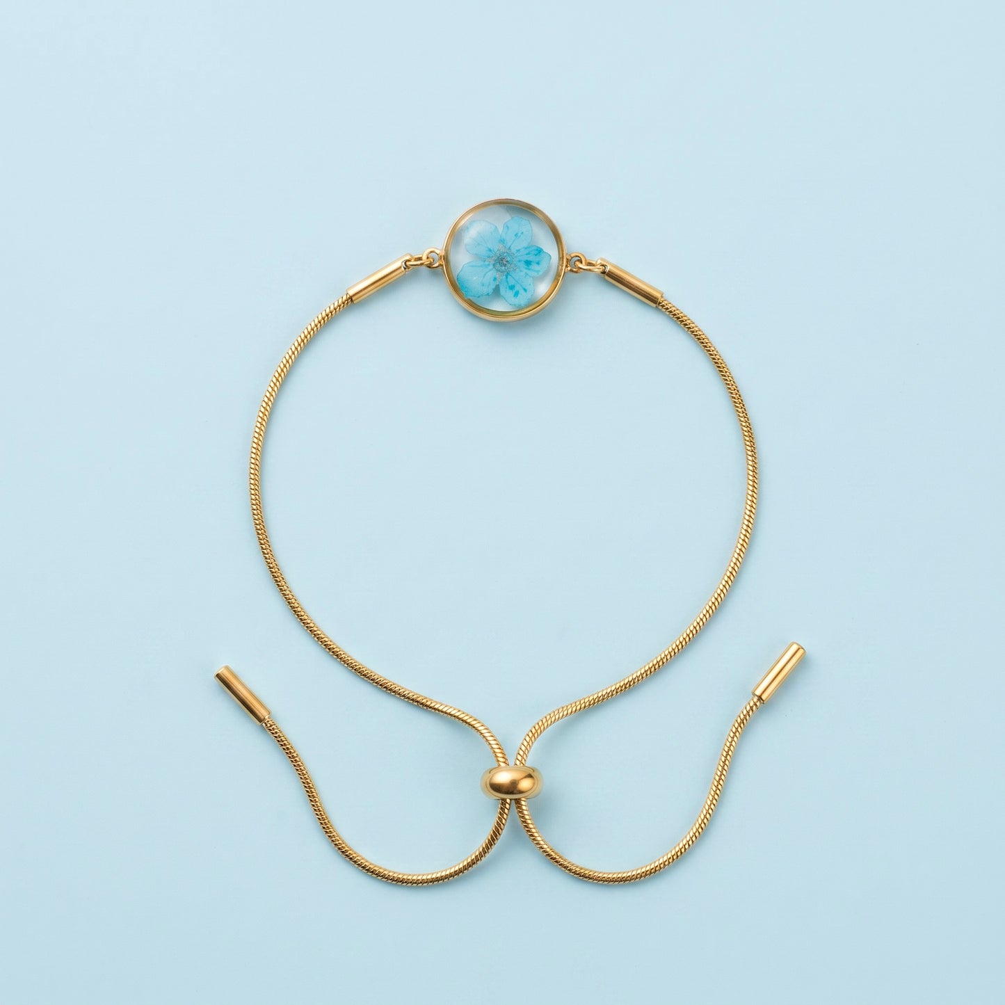Bracciale scorrevole in acciaio inox e fiore azzurro preservato nel ciondolo