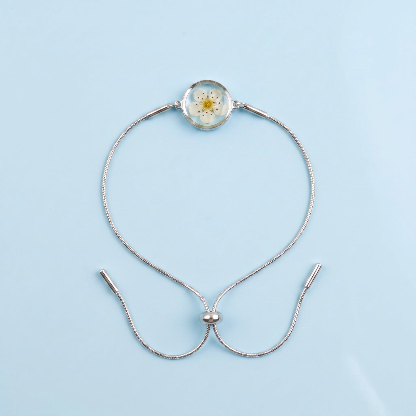 Bracciale scorrevole in acciaio inox e fiore bianco preservato nel ciondolo