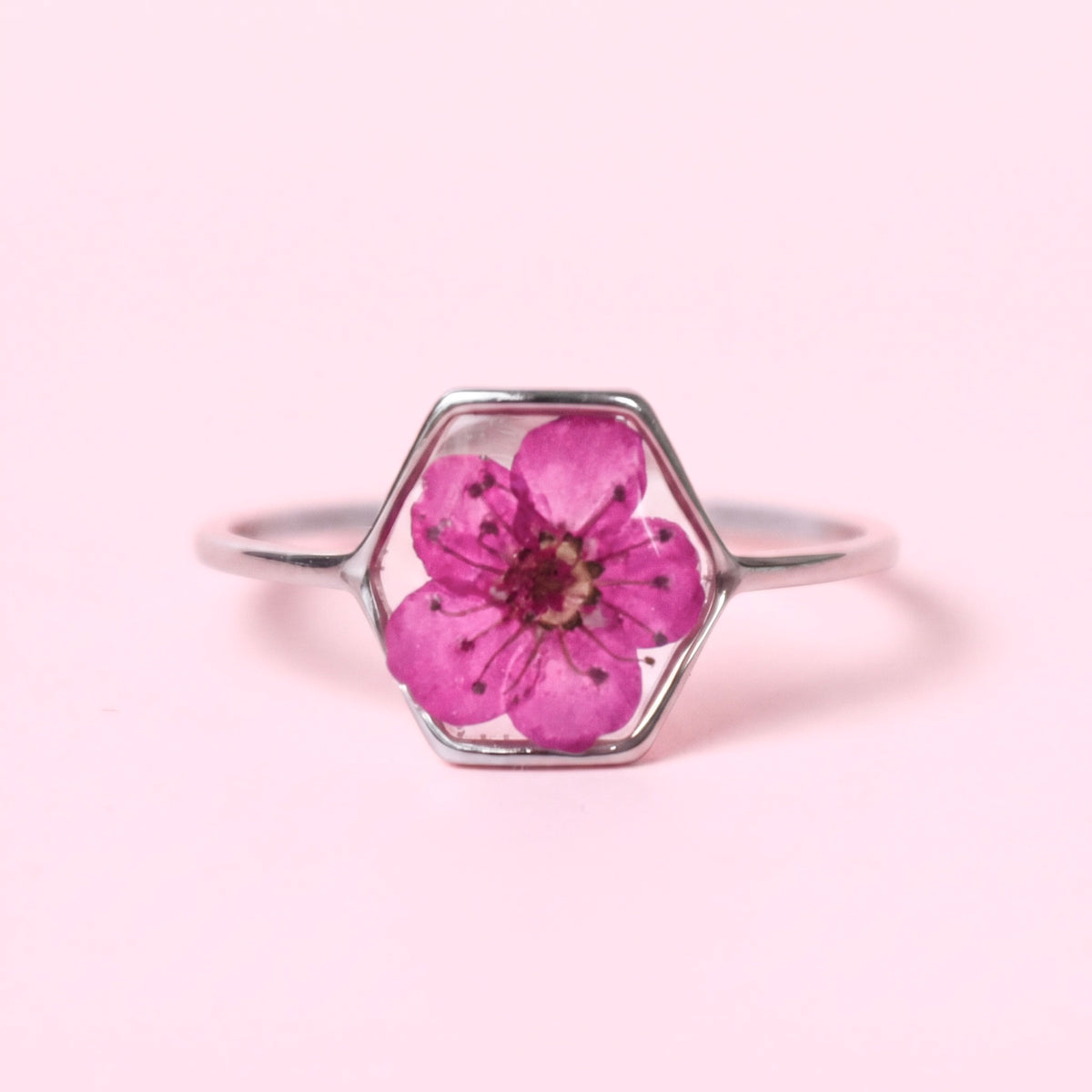 Anello in acciaio inox e fiore selvatico verde intersecato nella resina fucsia
