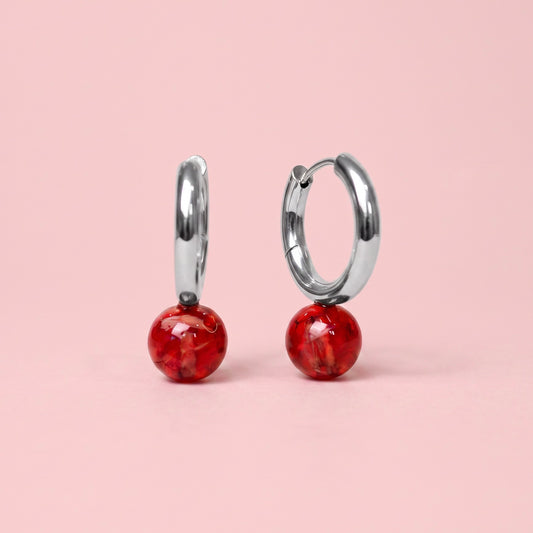 Orecchini a cerchio in acciaio inox con petali rossi preservati nella resina