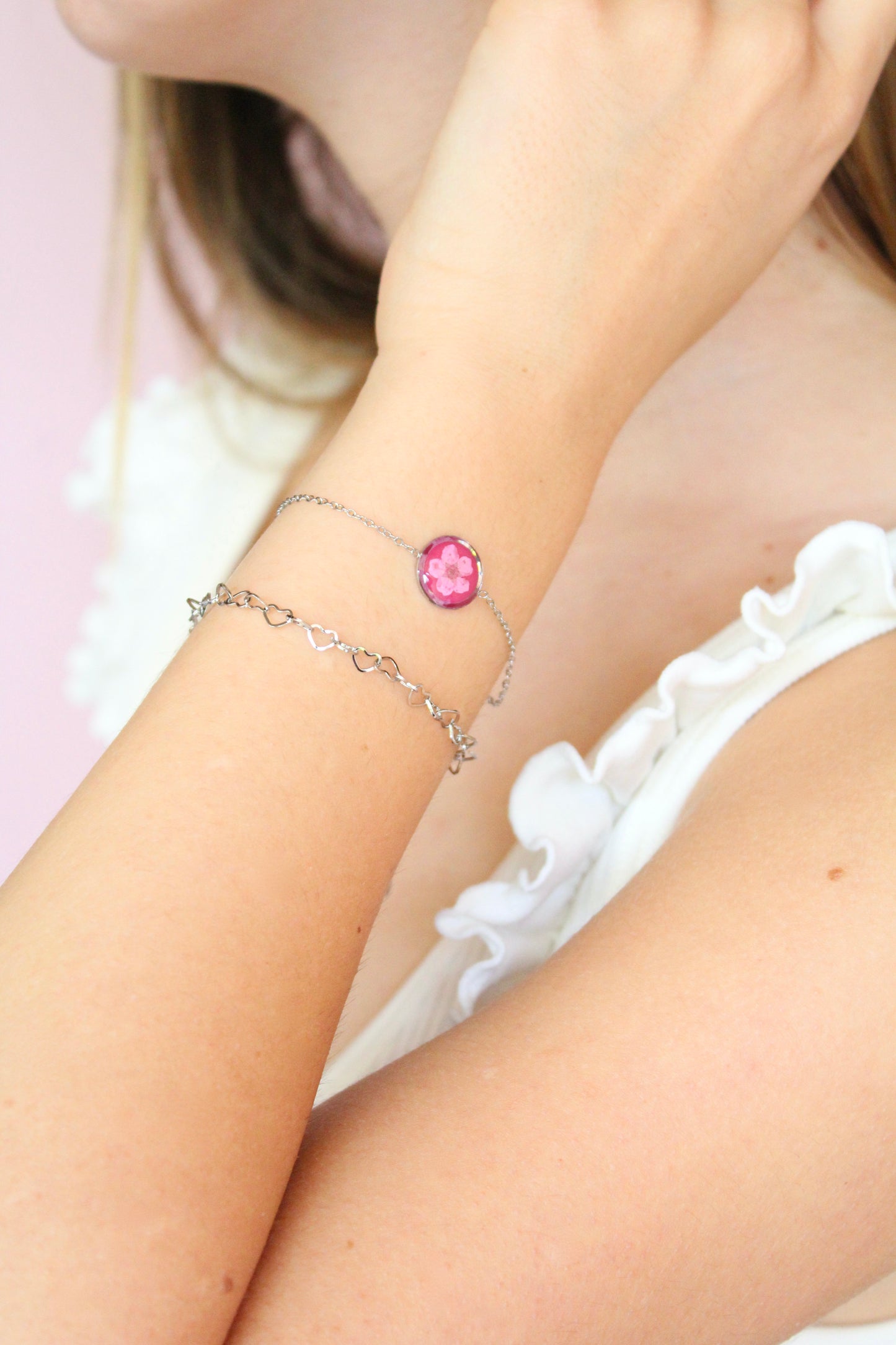 Set 2 bracciali in acciaio inossidabile con ciondolo in resina e fiore selvatico rosa, sfondo fucsia